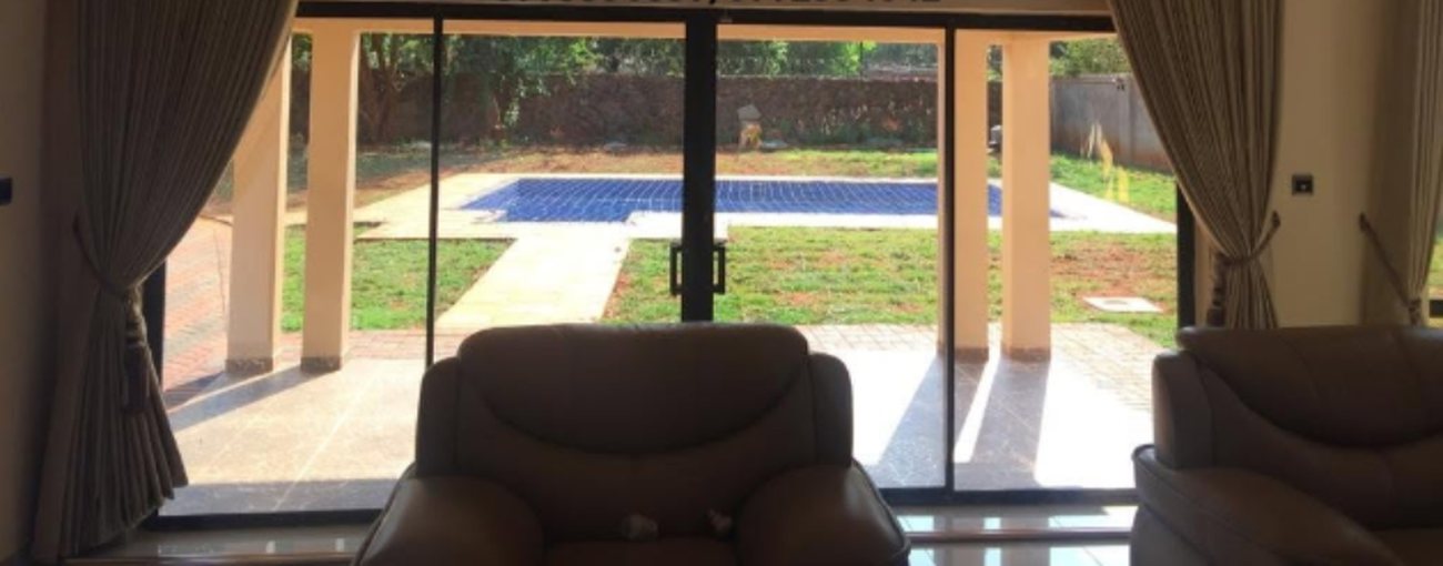 Sliding aluminium doors and curtaining opening a lounge onto a pool and garden